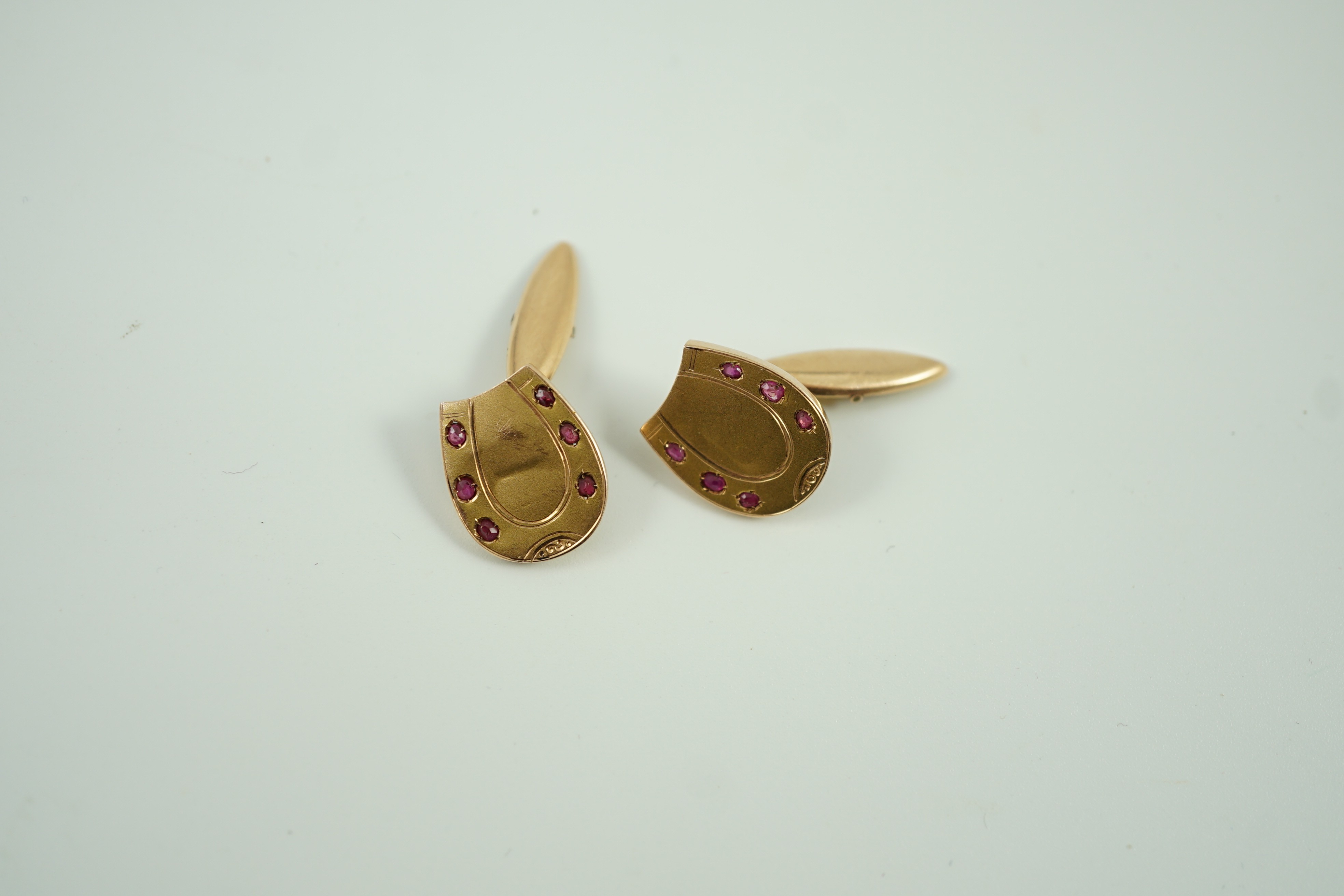 A pair of early 20th century Russian 56 zolotnik yellow metal and ruby set horseshoe shaped cufflinks, 16mm, gross weight 3.9 grams.